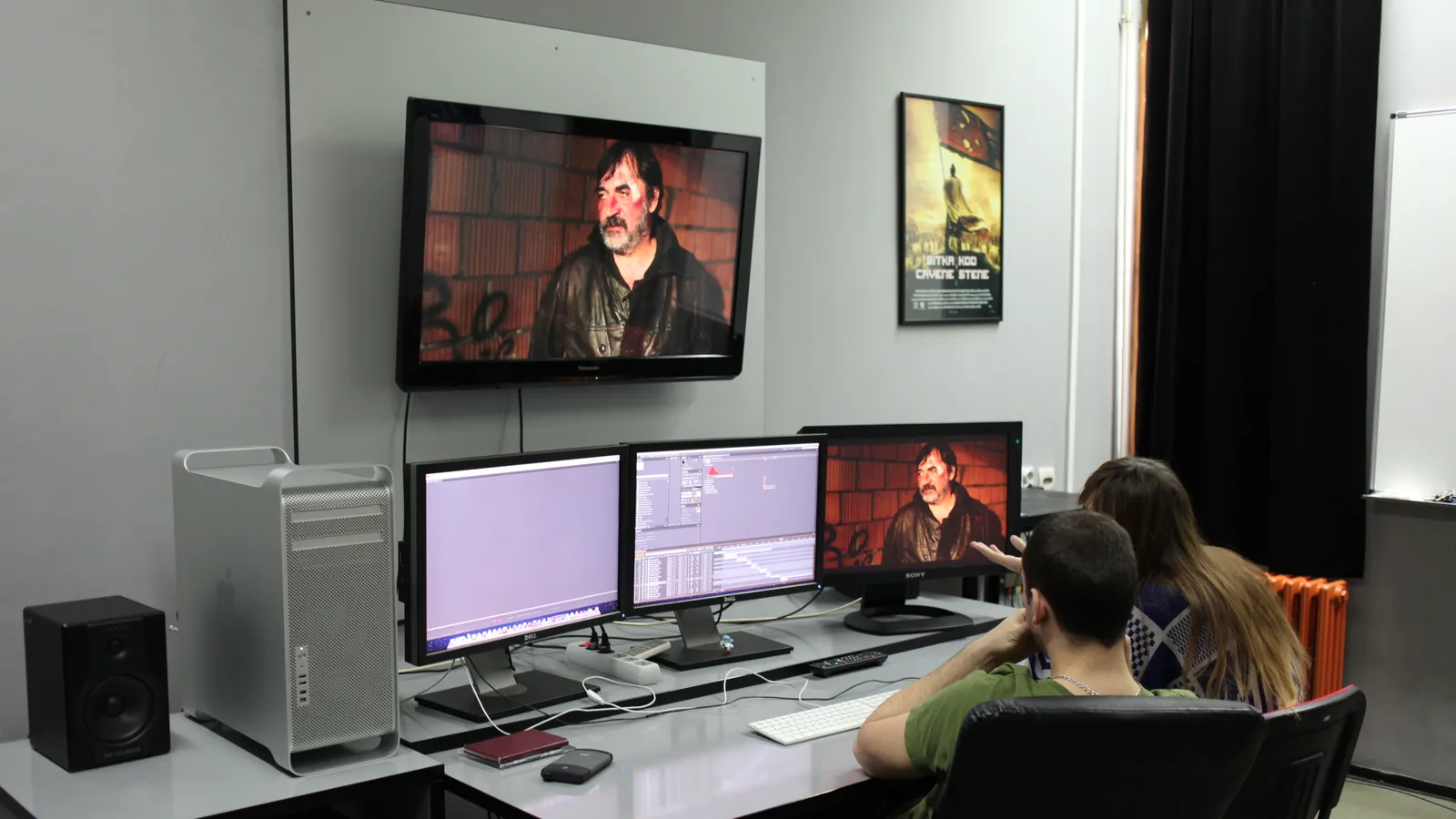 Students working at editing workstations with several monitors in a university film editing department.