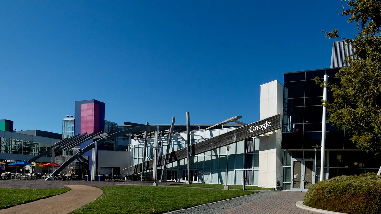Buildings and walkways on the Googleplex campus in Mountain View under a clear blue sky.