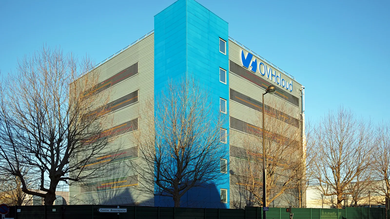 The blue OVHcloud data center building on rue Kellermann in Roubaix, with bare trees in front.