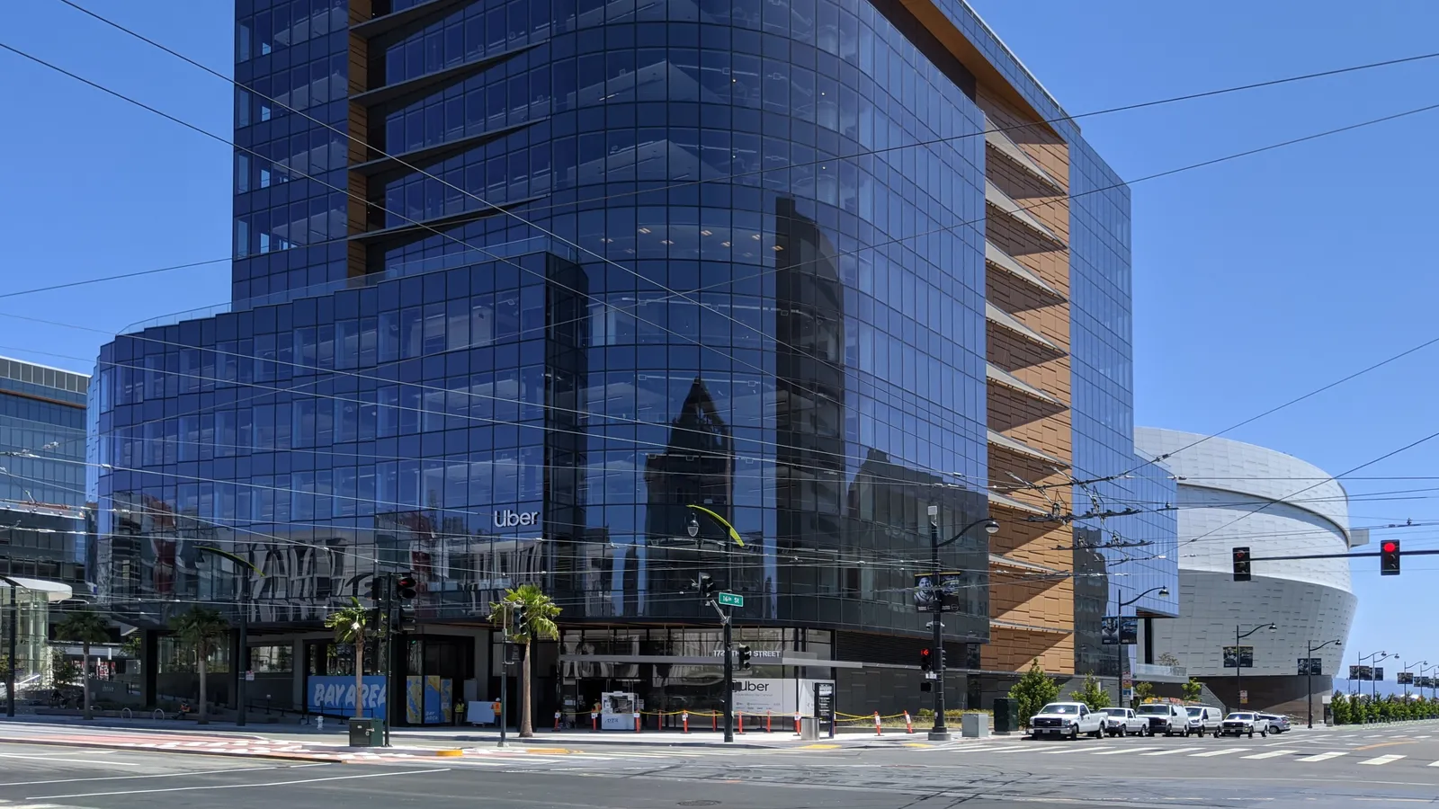 The glass Uber office buildings in the Mission Bay neighborhood of San Francisco under a blue sky.