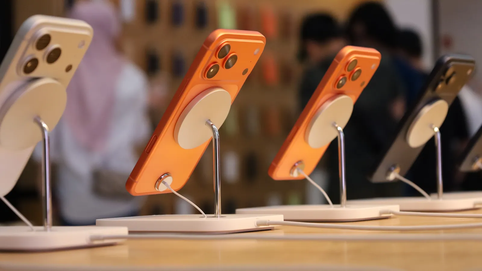 Orange iPhone 17 Pro handsets on display stands at an Apple Store launch in Malaysia
